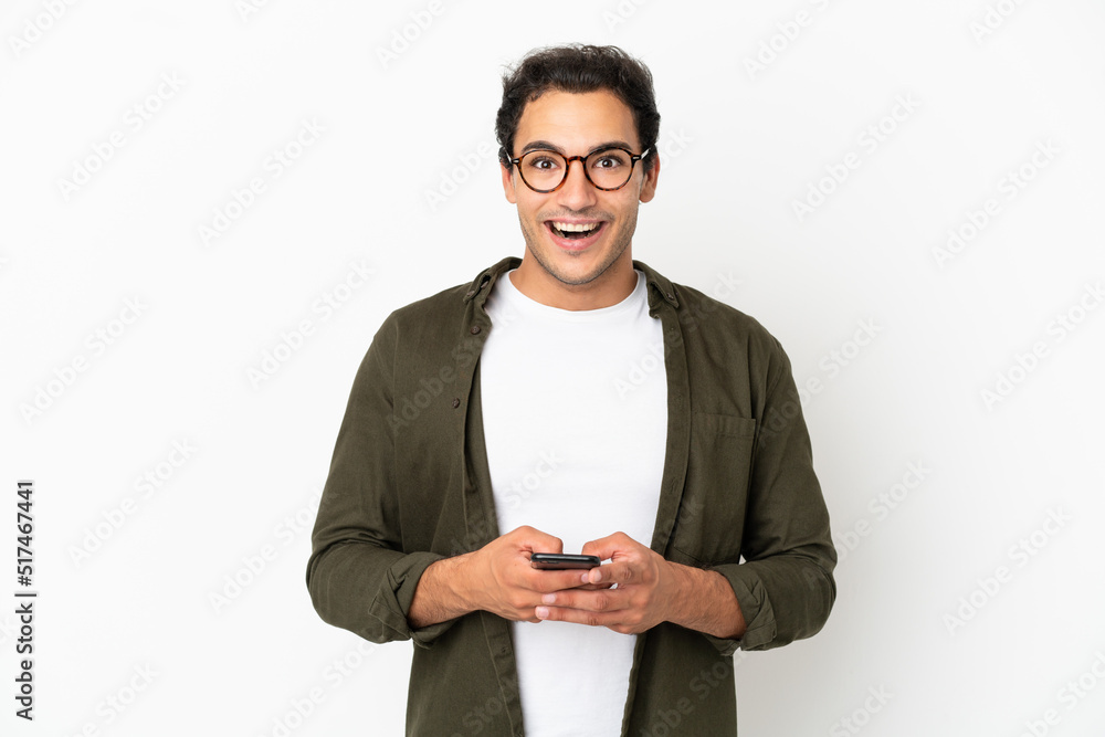 Caucasian handsome man over isolated white background surprised and sending a message Caucasian handsome man over isolated white background surprised and sending a message