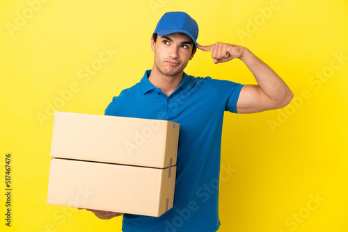 Delivery man over isolated yellow wall having doubts and thinking