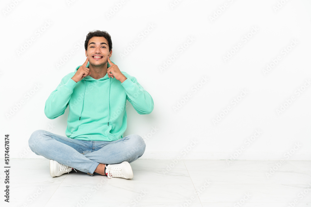 Caucasian handsome man sitting on the floor smiling with a happy and pleasant expression Caucasian handsome man sitting on the floor smiling with a happy and pleasant expression