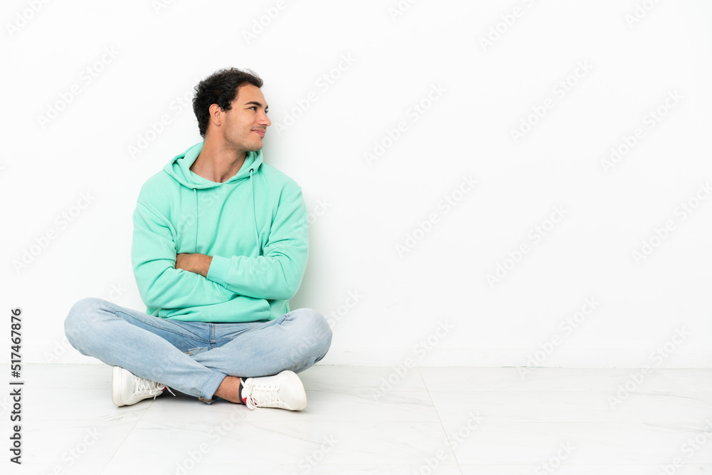 Caucasian handsome man sitting on the floor in lateral position Caucasian handsome man sitting on the floor in lateral position