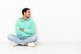 Caucasian handsome man sitting on the floor in lateral position