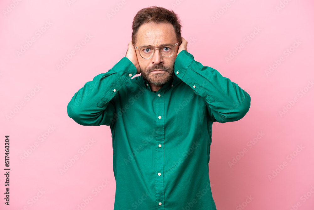 Middle age caucasian man isolated on pink background frustrated and covering ears Middle age caucasian man isolated on pink background frustrated and covering ears
