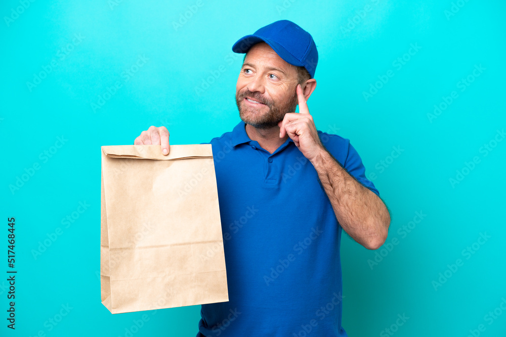 Middle age man taking a bag of takeaway food isolated on blue background thinking an idea while looking up Middle age man taking a bag of takeaway food isolated on blue background thinking an idea while looking up