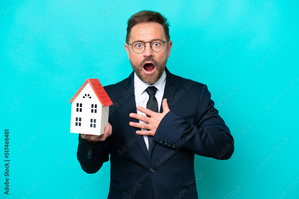 Real estate middle age agent man isolated on blue background surprised and shocked while looking right Real estate middle age agent man isolated on blue background surprised and shocked while looking right