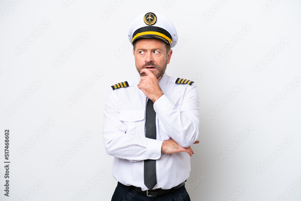 Airplane middle age pilot isolated on white background having doubts and with confuse face expression Airplane middle age pilot isolated on white background having doubts and with confuse face expression