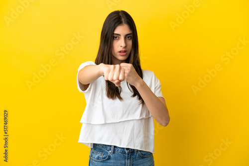 Young caucasian woman isolated on yellow background with fighting gesture © luismolinero