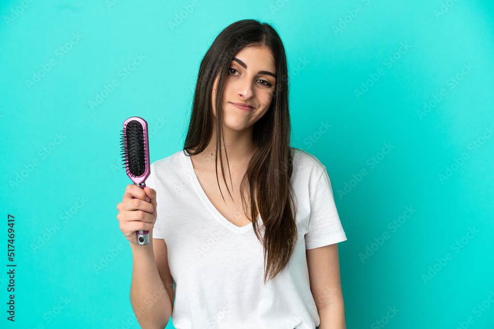 Young caucasian woman with hair comb isolated on blue background with sad expression Young caucasian woman with hair comb isolated on blue background with sad expression