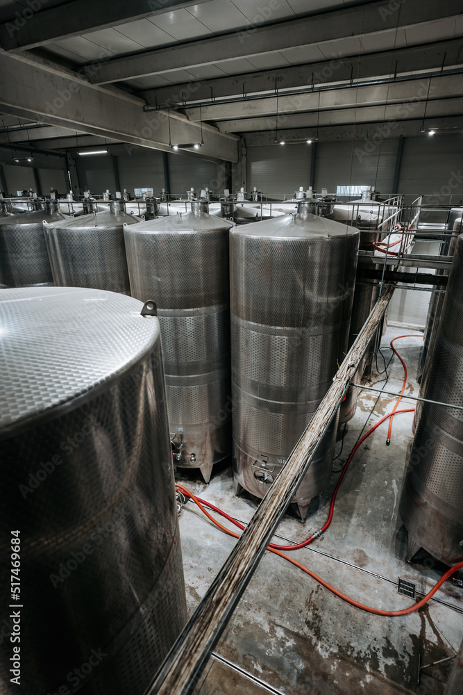 Huge warehouse for wine storing with giant stainless steel tanks. Industrial production of alcohol drink theme. Huge warehouse for wine storing with giant stainless steel tanks. Industrial production of alcohol drink theme.