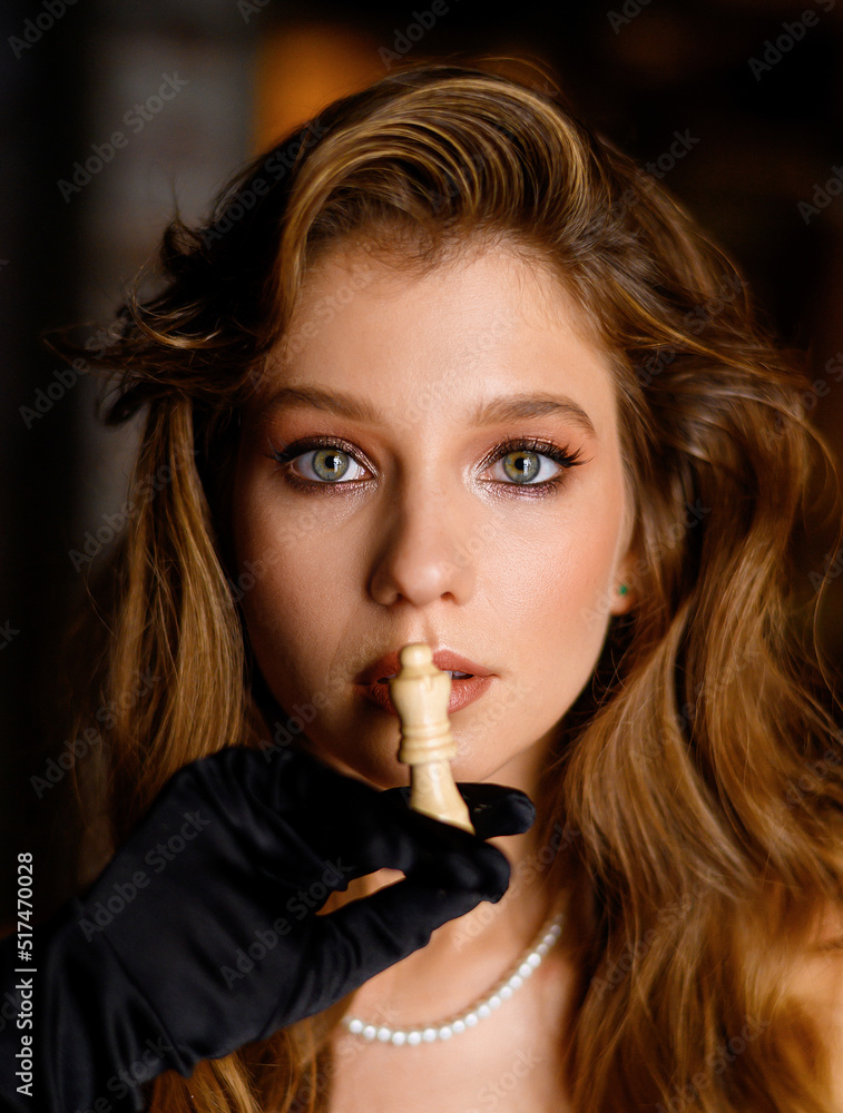 A beautiful Caucasian girl in a black dress poses with a chess piece. Fashion shooting A beautiful Caucasian girl in a black dress poses with a chess piece. Fashion shooting