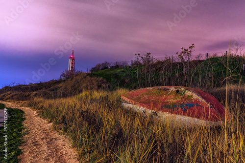 Boat on the beach at night. Lighthouse in the back. Beautiful landscape. photo