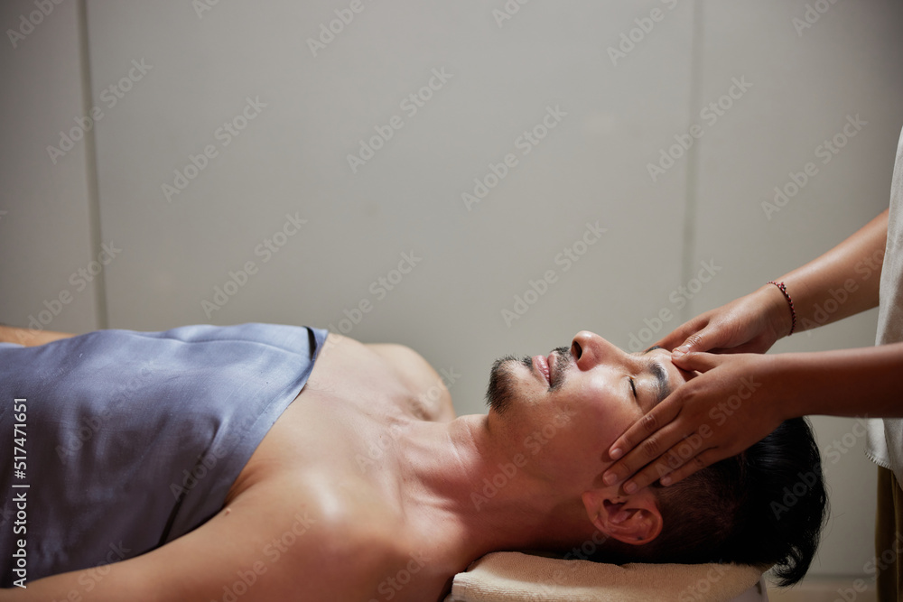 Face massage. Close-up of young man getting spa massage treatment at beauty spa salon. Spa skin and body care. Facial beauty treatment. Cosmetology.