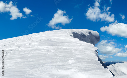 Winter mountain top with fairy overhang snow cap and human footprint on snowy mountainside follow up. photo