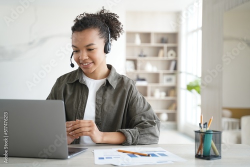 Biracial young girl student in headset learning online at laptop at home. Distance education © VK Studio