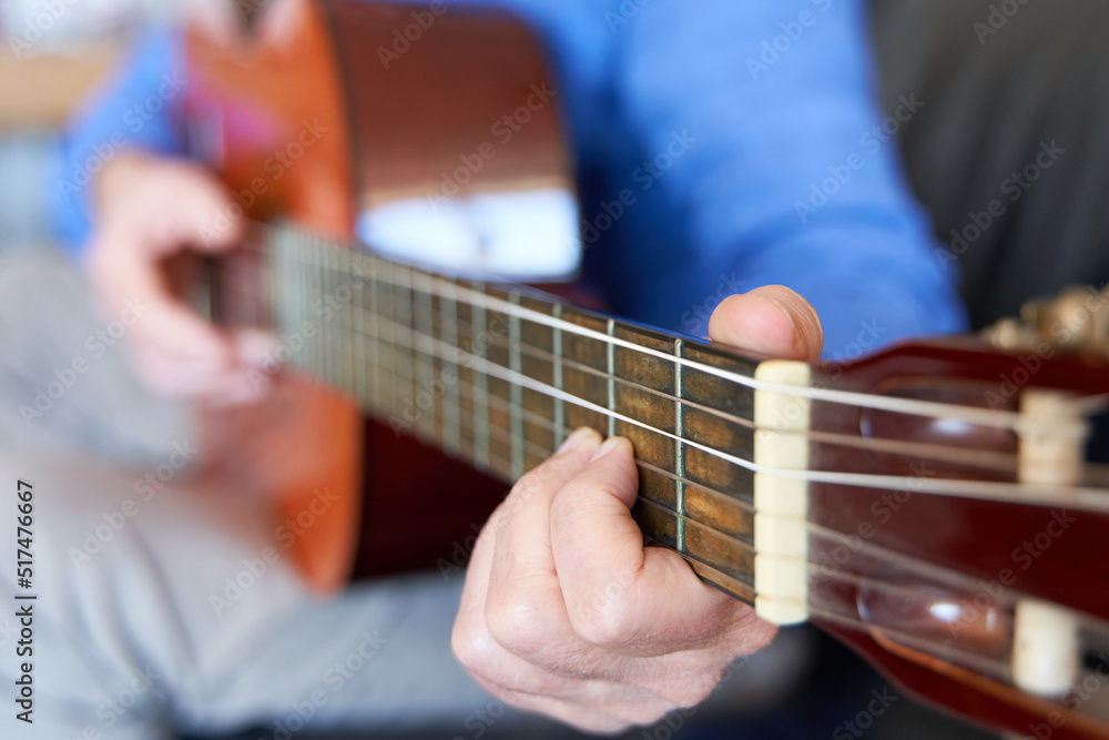 Mature male fingers in fretboard of classical guitar