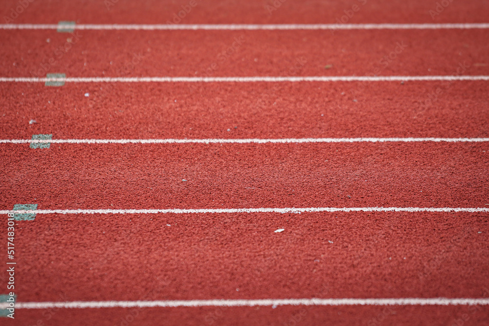 Fototapeta premium Running racetrack standard rubber surface with white lane outline. Sport and background photo. Selective focus.