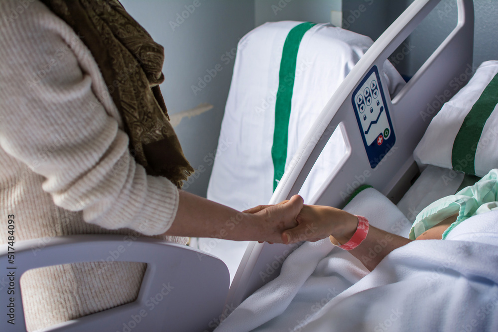 Woman holding the hand of a sick family member in the hospital. Unrecognizable people. Medicine Woman holding the hand of a sick family member in the hospital. Unrecognizable people. Medicine