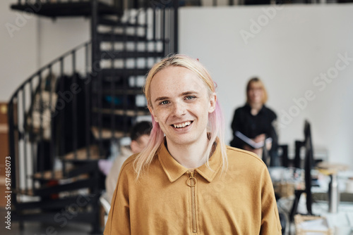 Portrait of smiling non-binary computer programmer with dyed long hair at tech start-up office photo