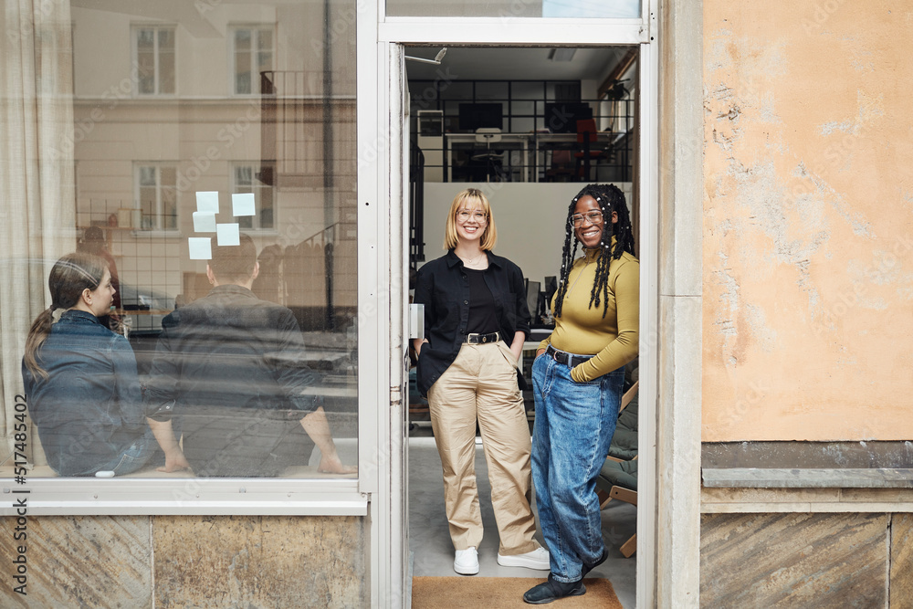 Female computer programmers standing at doorway of tech start-up office Female computer programmers standing at doorway of tech start-up office