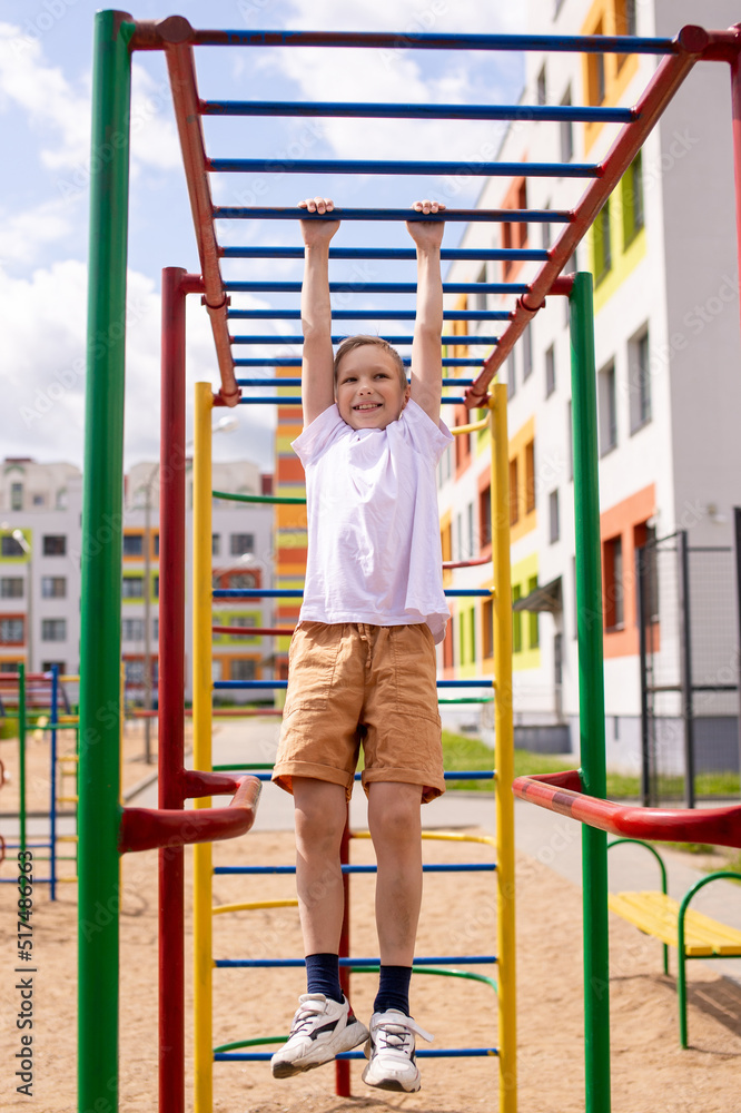Fototapeta premium A teenage boy is engaged on horizontal bars near the school