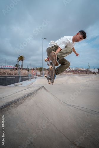 young skateboarder jumps over a ramp in a skate park. vertical composition