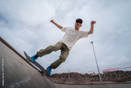 young male skater skates over the edge of a bowl at a skate park photo