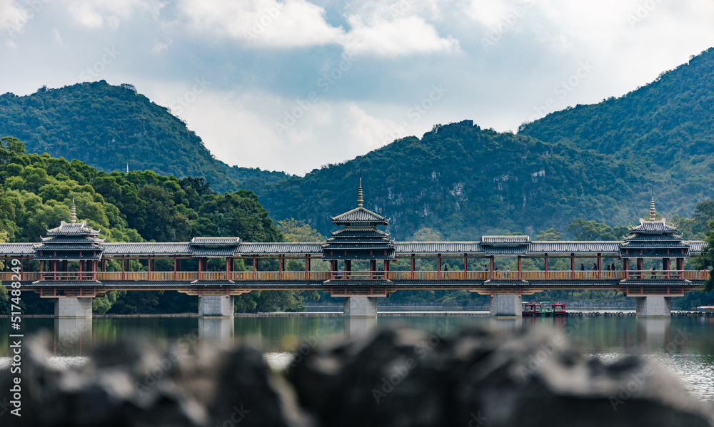 Naklejka premium An ancient bridge over a lake in a park in the South of China