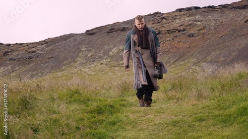 Stylish Man with a Sack Bag and a Banjo Case Walks Along the Green Meadow photo