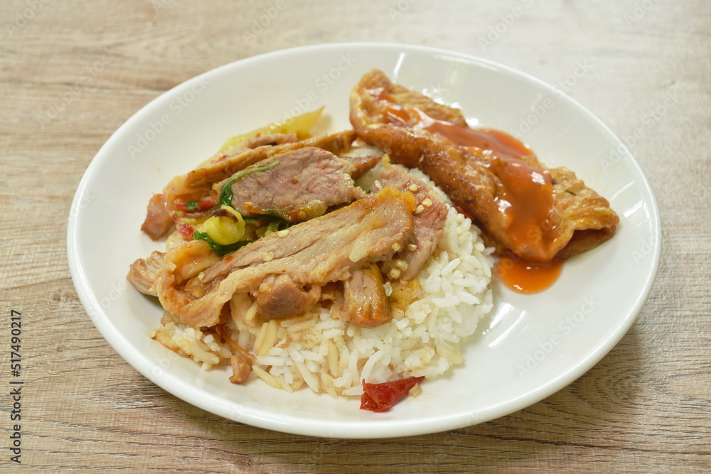 spicy stir fried barbecue pork neck with chili and basil leaf topping egg dressing sauce and rice on plate spicy stir fried barbecue pork neck with chili and basil leaf topping egg dressing sauce and rice on plate