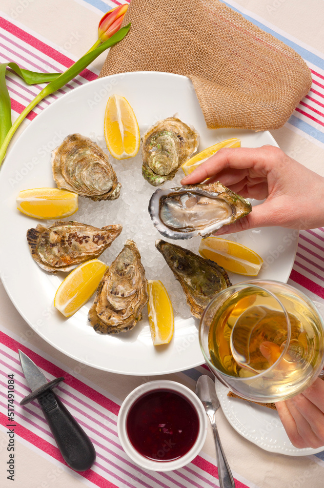 a girl eats oysters and drinks white wine in a restaurant