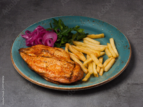 grilled chicken fillet with french fries, red onion and herbs