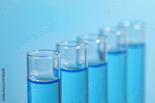Test tubes with reagents on light blue background, closeup. Laboratory analysis