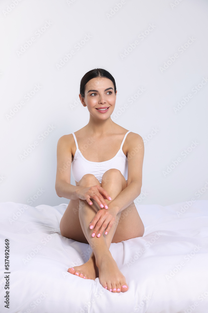 Young woman showing smooth skin after epilation on bed Young woman showing smooth skin after epilation on bed