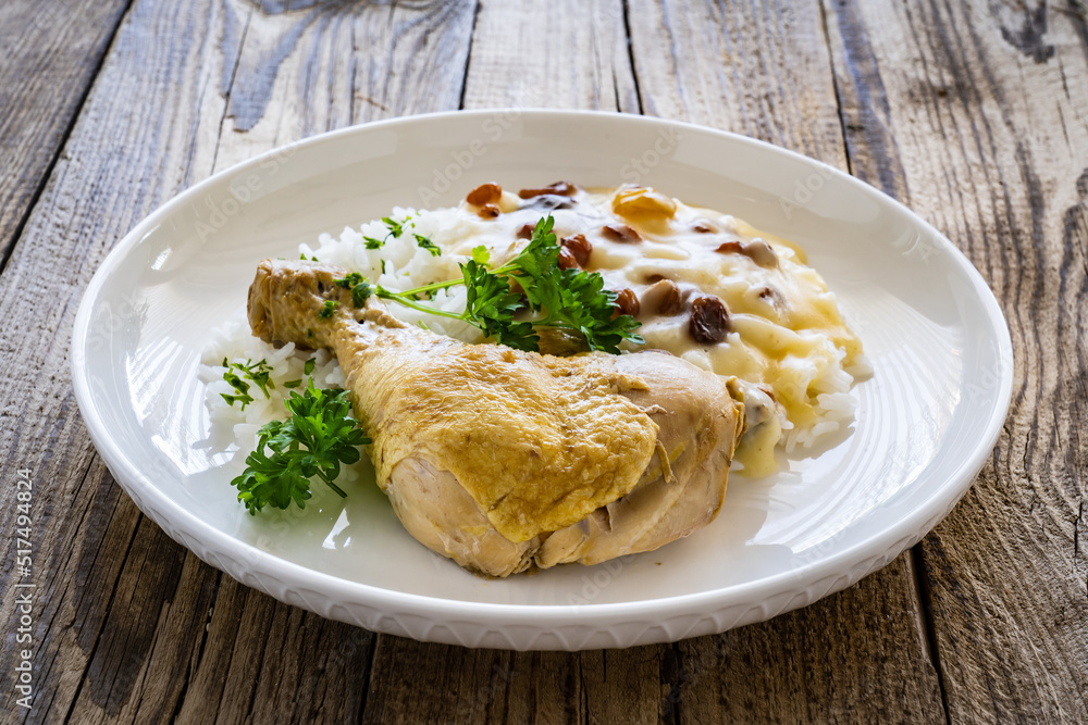 Boiled chicken thigh with white rice and lemon creamy sauce with raisins on wooden table Boiled chicken thigh with white rice and lemon creamy sauce with raisins on wooden table