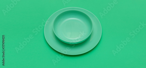 Green round empty plate with a dish on a green background. Inserting text about a restaurant or green diet.