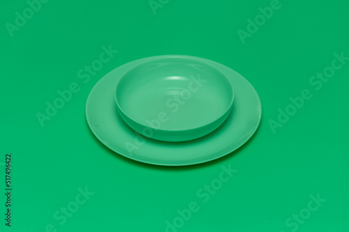Green round empty plate with a dish on a green background. Inserting text about a restaurant or a diet.