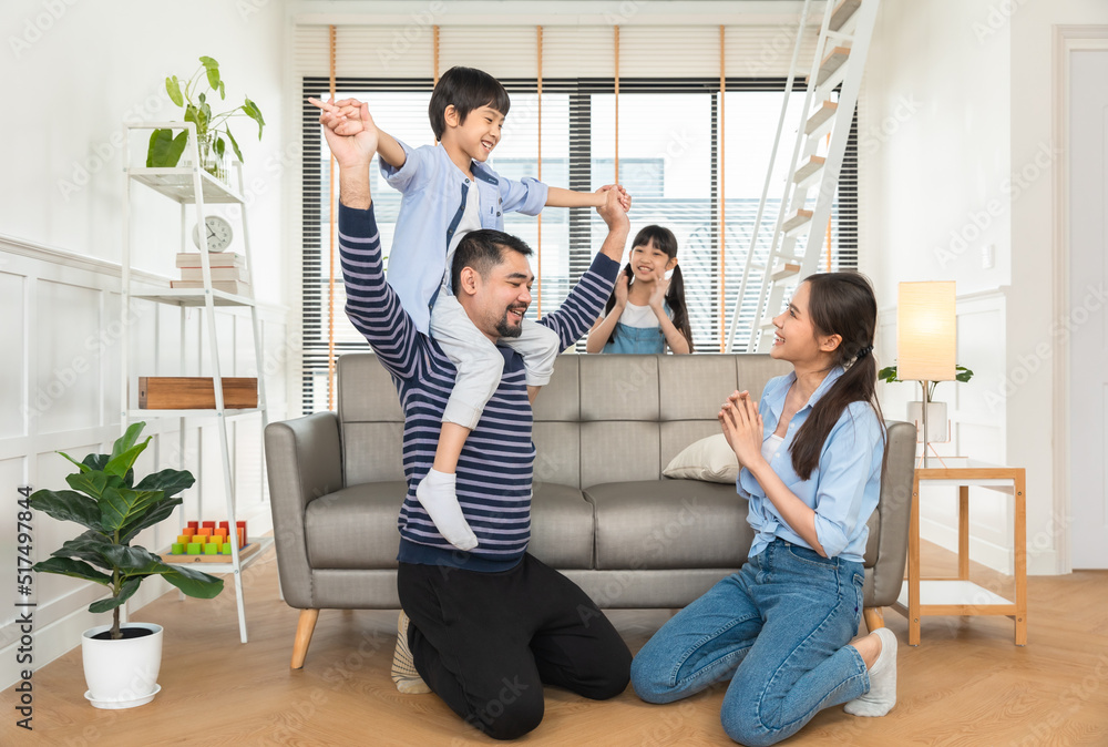 Fototapeta premium Happy dad lifting excited daughter girl playing airplane with flying open hand in living room.Asian family home entertainment concept.