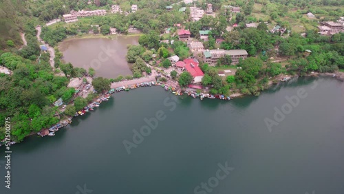 aerial drone forward movement shot while focussing on the boat house and boats in water over blue green water showing the beauty of naukuchiatal bhimtal lake in nainital district uttarakhand India photo