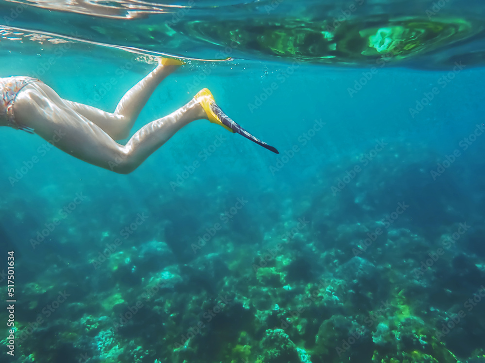 A woman snorkeling underwater in the bright blue Pacific Ocean in Maui Hawaii while on vacation or holiday in the summer