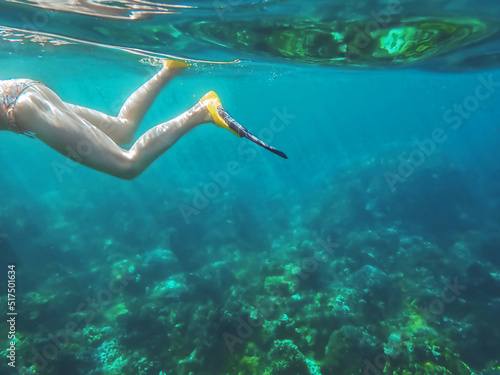 A woman snorkeling underwater in the bright blue Pacific Ocean in Maui Hawaii while on vacation or holiday in the summer