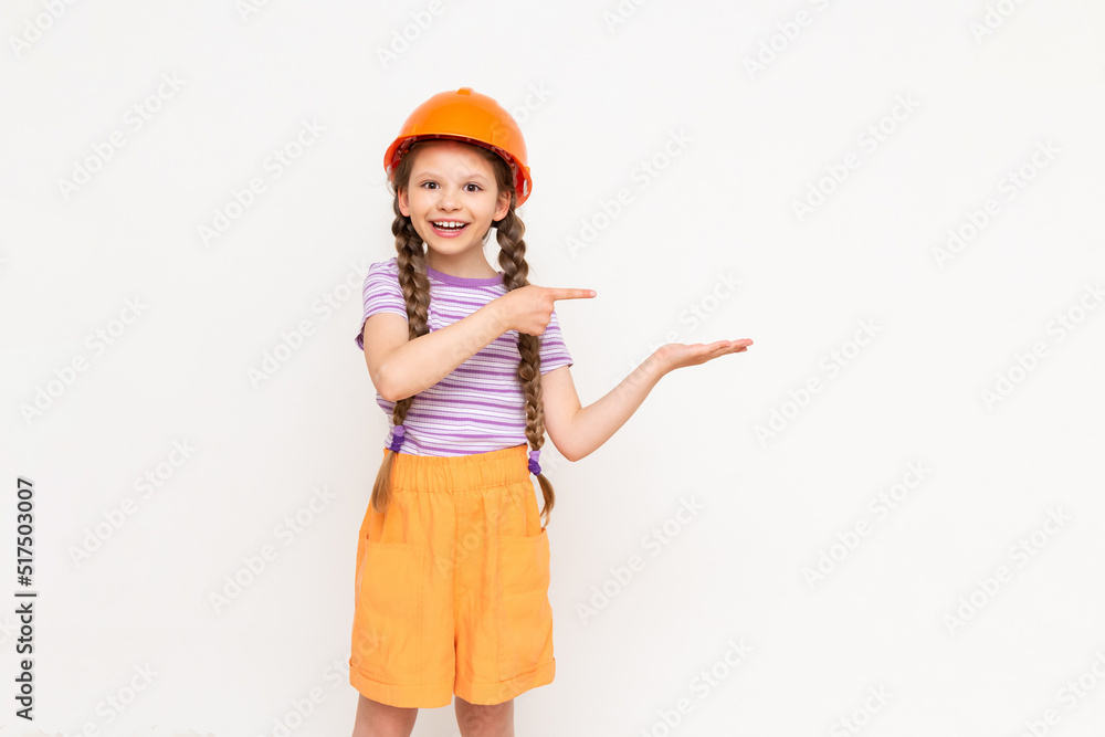 A little girl in a construction helmet holds your advertisement on her hand on a white isolated background. The concept of renovation in the children's room. A little girl in a construction helmet holds your advertisement on her hand on a white isolated background. The concept of renovation in the children's room.