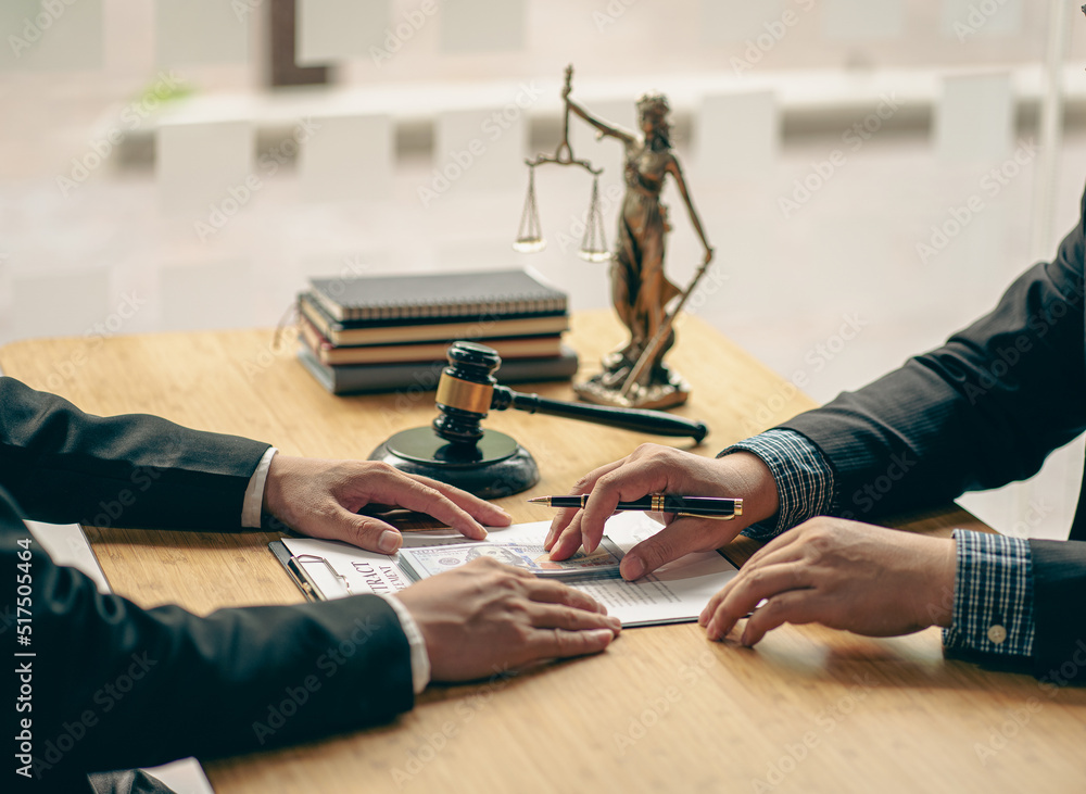 Fototapeta premium A meeting of professional business women and male lawyers working and discussing at the judge's hammered office with the scales of justice laid alongside the concept of law and consulting services.