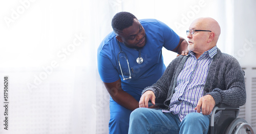 Professional doctor helps an elderly man with chronic diseases. Therapist and patient in home interior. Health care and medicine concept.