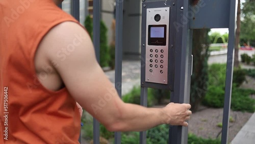 Male using intercom at residential building complex entrance. opens electronic code lock. man hand entering security system code, pressing button with index finger intercom device entrence door. photo