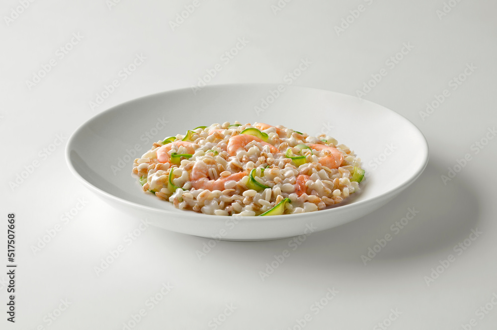 Barley spelled rice risotto with shrimp and zucchini in white bowl Barley spelled rice risotto with shrimp and zucchini in white bowl