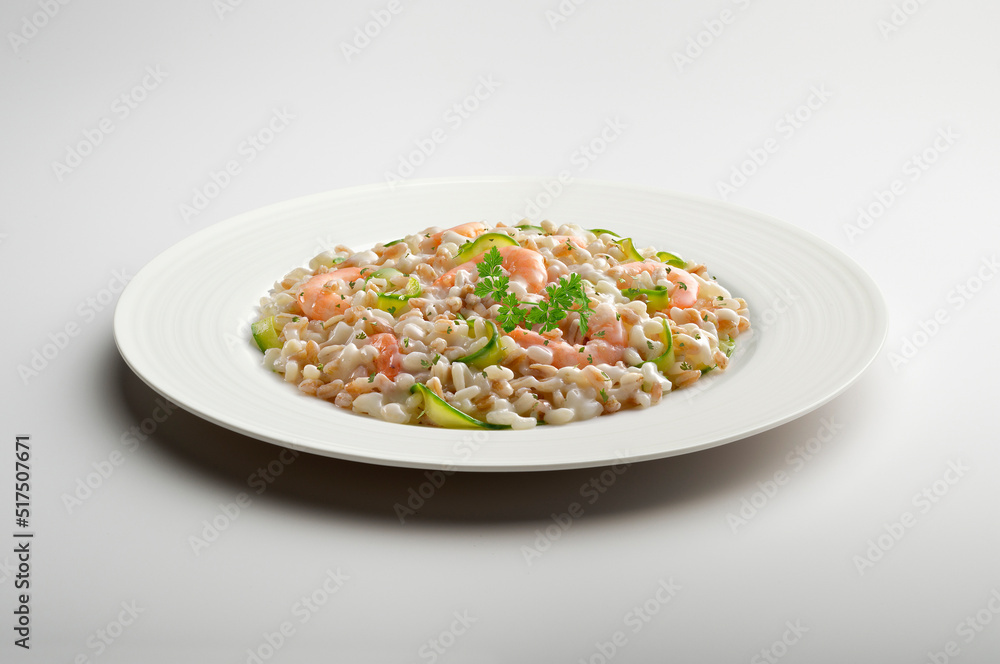 Barley spelled rice risotto with shrimps and courgettes and parsley in white plate Barley spelled rice risotto with shrimps and courgettes and parsley in white plate