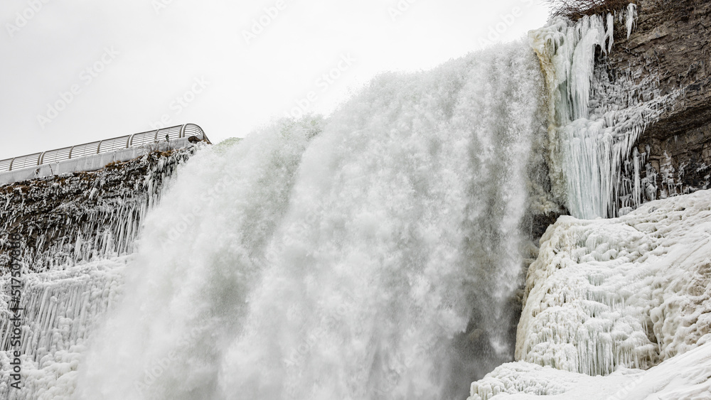 American Falls at Niagara Falls are pouring water through frozen landscape at winter