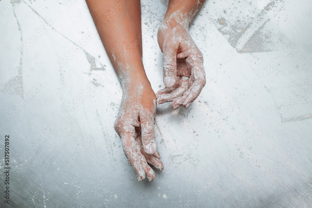 Fototapeta premium baker's hands in flour on the metallic table
