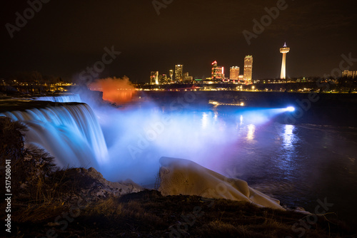 Night illumination on American Falls at Niagara Falls are pouring water through frozen landscape at winter