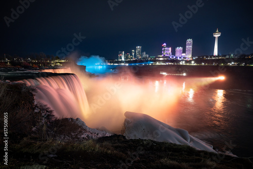 Night illumination on American Falls at Niagara Falls are pouring water through frozen landscape at winter