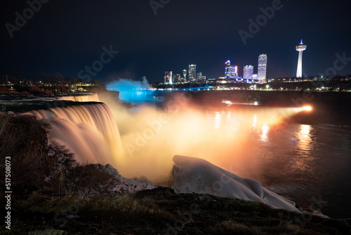 Night illumination on American Falls at Niagara Falls are pouring water through frozen landscape at winter